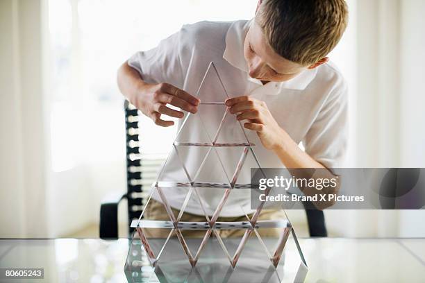 boy building house of cards - card house stock pictures, royalty-free photos & images