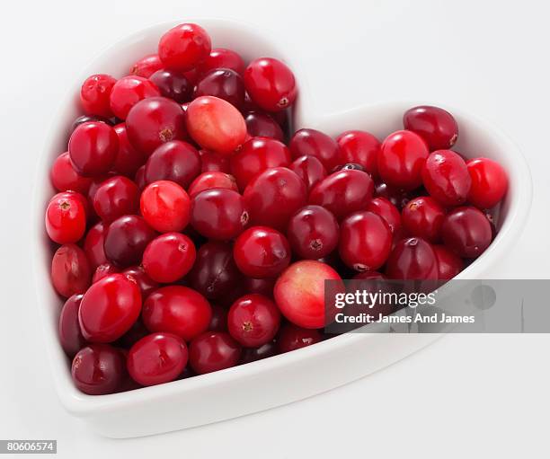 cranberries in heart-shaped bowl - cranberry heart stock-fotos und bilder