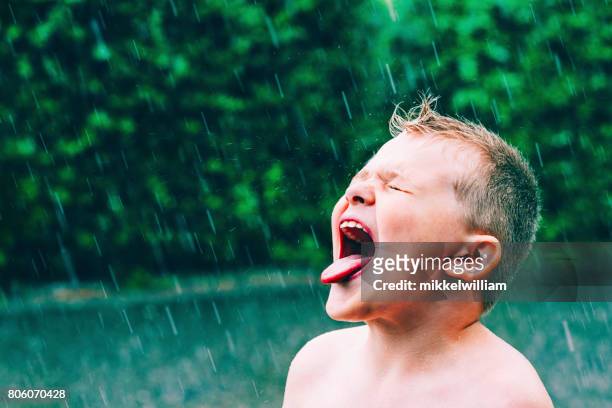 sommerregen gießt und junge schmeckt die regentropfen - enjoy monsoon stock-fotos und bilder
