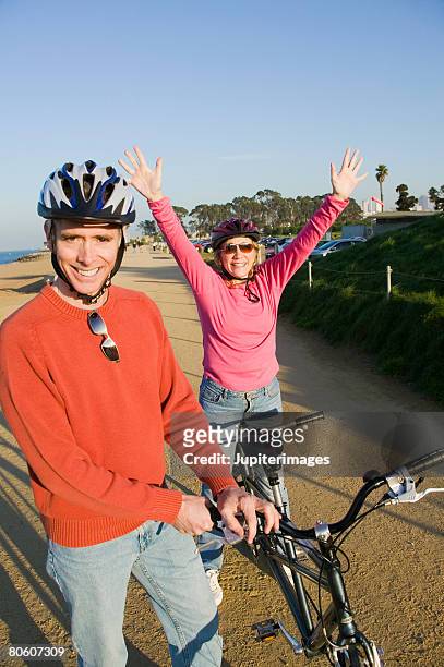 happy couple standing by tandem bike - freihändiges fahrradfahren stock-fotos und bilder