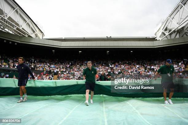 The rains covers are pulled across centre court during the Gentlemen's Singles first round match between Andy Murray of Great Britain and Alexander...