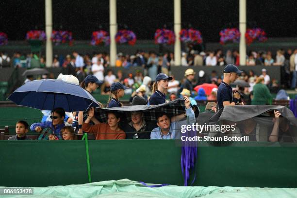 Spectators attempt to keep dry on day one of the Wimbledon Lawn Tennis Championships at the All England Lawn Tennis and Croquet Club on July 3, 2017...