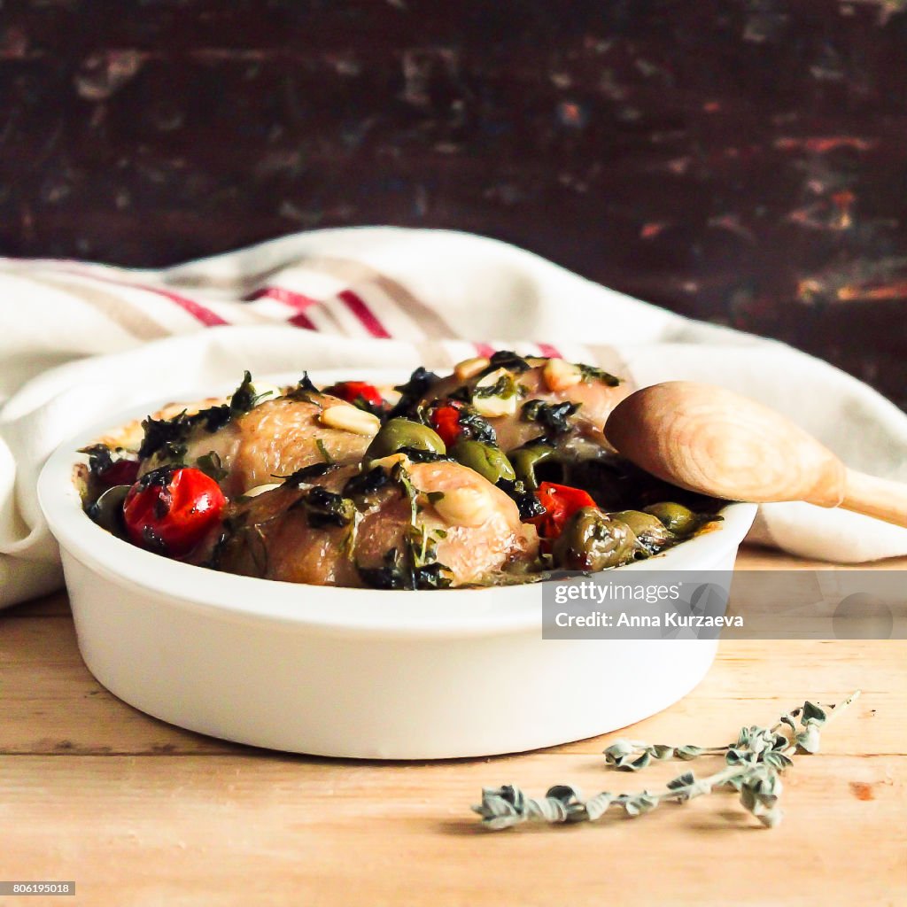 Roasted chicken meat with green olives and cherry tomatoes in a bowl, selective focus