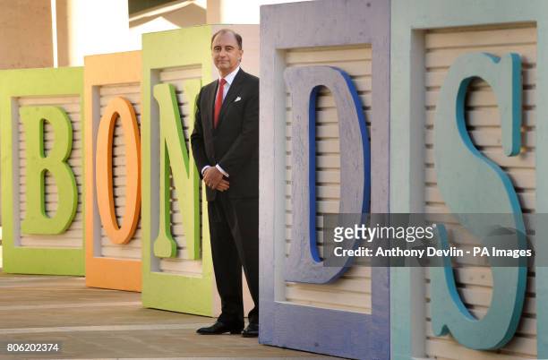 Chief Executive of the LSE, Xavier Rolet, poses bedside signage outside the London Stock Exchange, to promote a new electronic retail bond service.