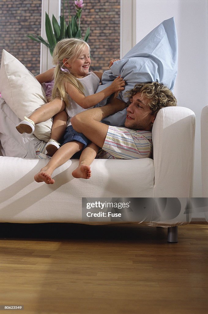 Father and his daughter having pillow fight