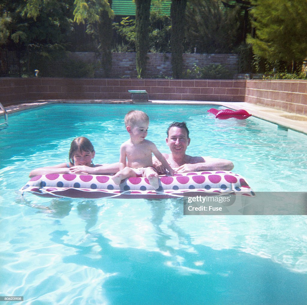Parents with little son at airbed in swimming pool