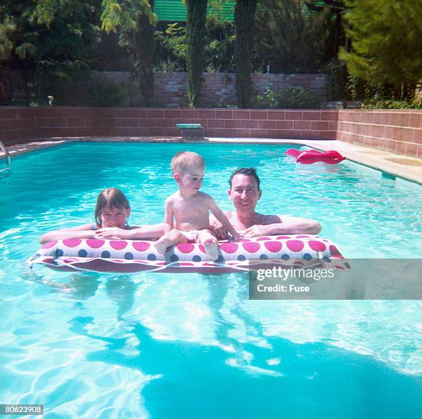 parents with little son at airbed in swimming pool - women swimming pool retro stock pictures, royalty-free photos & images