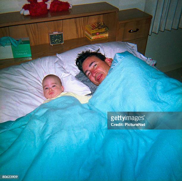 father lying with little son in bed - 1950s bedroom stock pictures, royalty-free photos & images