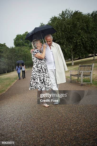 couple sharing an umbrella - sharing umbrella stock pictures, royalty-free photos & images