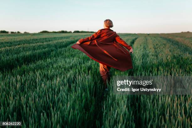 woman in red coat  walking  in the field at sunset - fashion model walking stock pictures, royalty-free photos & images