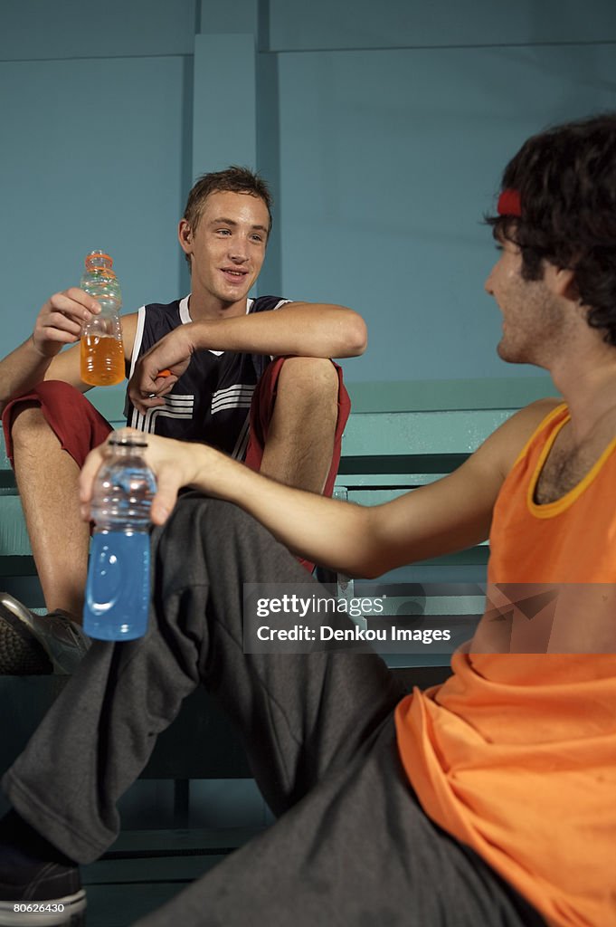 Two young men looking at each other and holding sport drinks