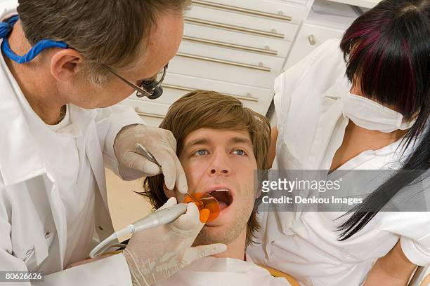 young man undergoing dental treatment - human teeth stock pictures, royalty-free photos & images