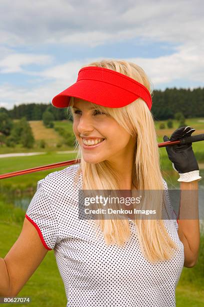 mid adult woman holding a golf club and smiling - sun visor stock pictures, royalty-free photos & images