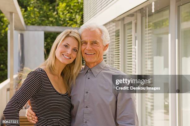 portrait of a senior man and a young woman embracing each other and smiling - old man young woman stockfoto's en -beelden