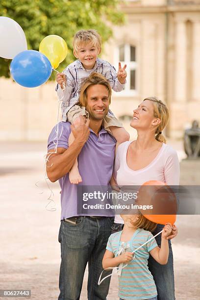 young man carrying his son on his shoulders and his wife and daughter looking at him - flirt barefoot blonde stock-fotos und bilder