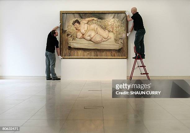 Christie's employees hold a painting entitled 'Benefits Supervisor Sleeping' by German artist Lucian Freud at Christie's auction house in London, on...
