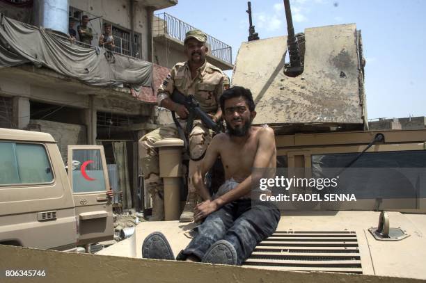 An Iraqi soldier sits on a tank with a man alleged to be an Islamic State group member in the Old City of Mosul on July 3 during the government...