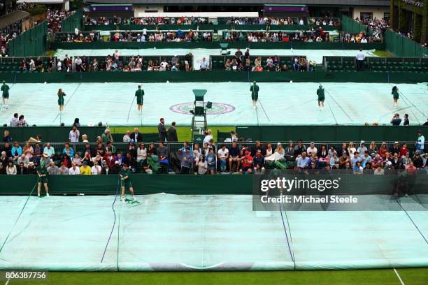 The groundstaff remove the covers off courts after a stop due to rain on day one of the Wimbledon Lawn Tennis Championships at the All England Lawn...