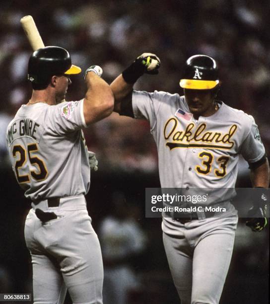 Jose Canseco of the Oakland Athletics is congratulated by Mark McGwire of the Oakland Athletics after hitting a home run against the Cincinnati Reds...