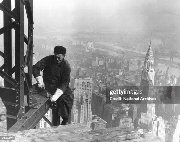 Construction worker bolts beams during construction of the Empire State Building, New York City, circa 1930. In the background is the Chrysler...