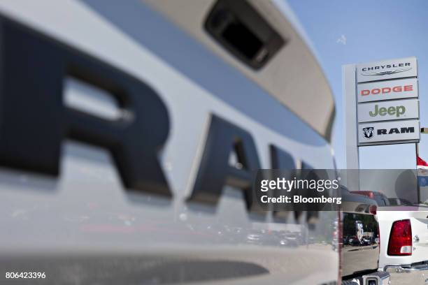 Sign stands near a row of Fiat Chrysler Automobiles Dodge Ram pickup trucks at a car dealership in Moline, Illinois, U.S., on Saturday, July 1, 2017....