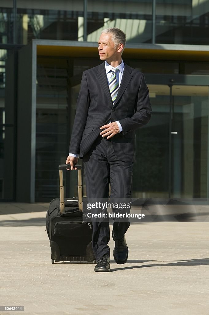 Full body portrait of mature businessman with carry-on suitcase