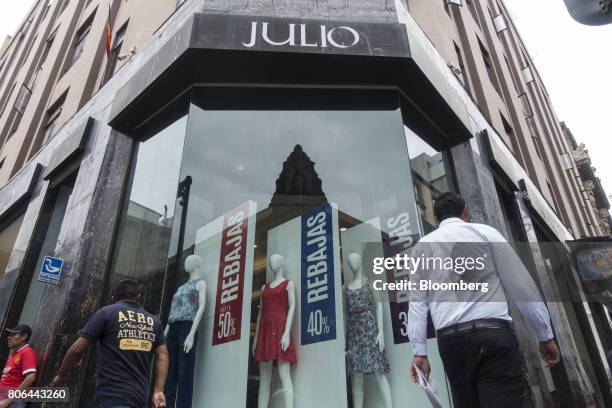 Pedestrians pass in front of sale signs displayed in the window of a Julio clothing store on Francisco I. Madero Avenue in Mexico City, Mexico, on...