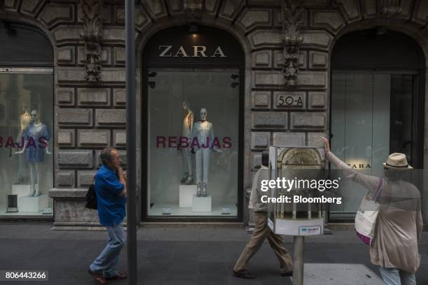 Pedestrians pass in front of a sale sign displayed in the window of a Zara store, operated by Inditex SA, on Francisco I. Madero Avenue in Mexico...