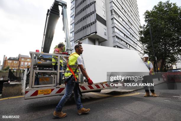 Workers remove panels of external cladding from the facade of Braithwaite House in London, on July 3 in the wake of the Grenfell Tower fire....