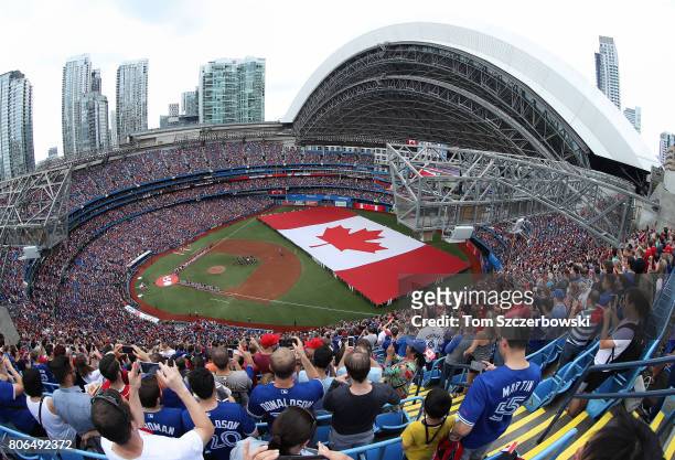 General view of the Rogers Centre as a large Canadian flag is unfurled in the outfield on Canada Day during the playing of the Canadian national...