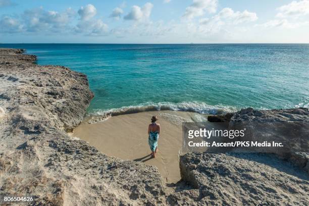 woman discovers empty beach between rocks - aruba beach stock-fotos und bilder