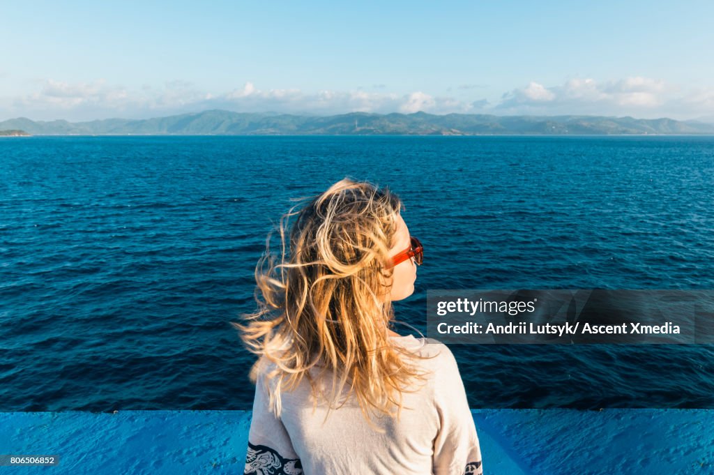 Woman relaxes during ferry crossing, sunrise