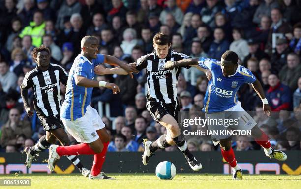 Joey Barton of Newcastle battles with Portsmouth's French footballer Sylvain Distin and Portsmouth's Ghanaian footballer Sulley Muntari during a...