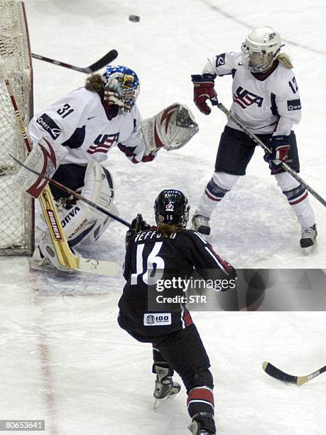 Jayna Hefford of Canada sends a shot pass goalkeeper Jessie Vetter and Jenny Potter of the United States during the goal medal game at the 2008...