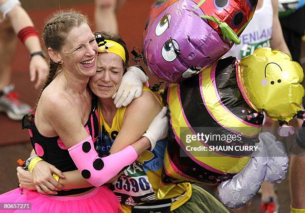 Participants in the London Marathon hug after crossing the finish line along The Mall near Buckingham Palace in London on April 13, 2008. Martin...