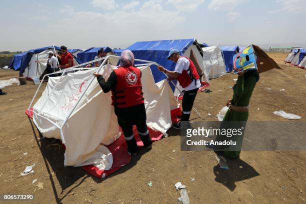 United Nations teams and Lebanese Red Cross staff build a tent within the infrastructure works at the Qob Elias refugee camp after a big fire broke...