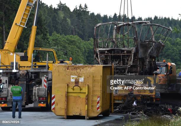 The tour bus which burst into flames, is removed following a collision with a trailer truck on the highway A9 near Münchberg, southern Germany, on...