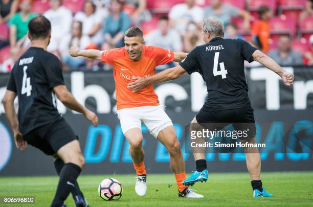 Lukas Podolski of Nowitzki All Stars is challenged by Karl-Heinz Koerbel of Schumacher and Friends during the Champions for Charity Friendly match at...