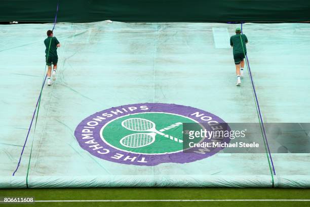 The groundstaff remove the covers off courts after a stop due to rain on day one of the Wimbledon Lawn Tennis Championships at the All England Lawn...