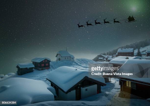 santa's sledge in a starry sky over a village in the snow - cuento de hadas fotografías e imágenes de stock