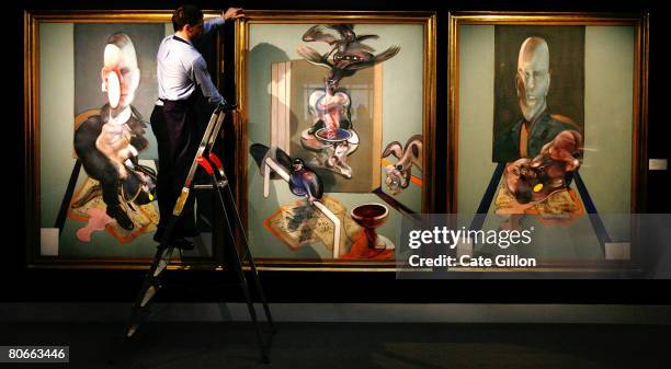 Sotheby's employee poses in front of Francis Bacon's triptych on April 14, 2008 in London, England. The artwork, estimated to sell for 70 million...