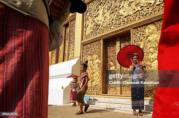 Laos girls in acient custome stand next to The Funerary Carriage House at Wat Xieng Thong during the Songkran festival on April 14 in Luang Prabang,...