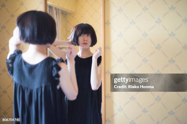 woman standing front of mirror - rieko honma stock-fotos und bilder