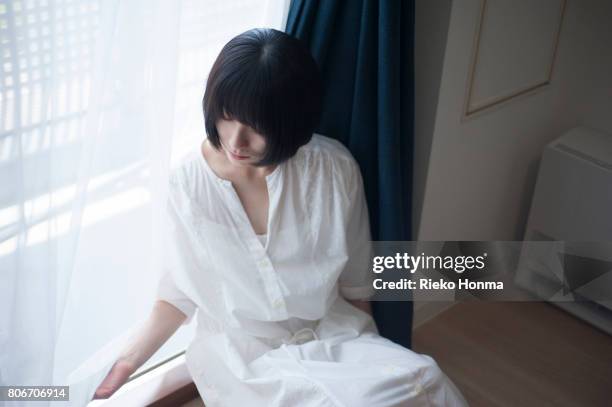 young woman sitting by the window - 前髪 ストックフォトと画像