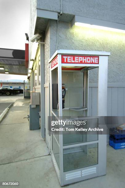 Side view of an empty telephone booth on the side of a gas station, USA, mid-1990s.