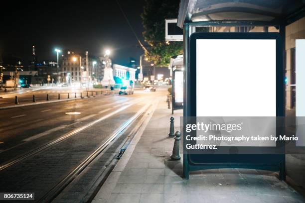 bus stop with billboard at night - billboard night road stock pictures, royalty-free photos & images