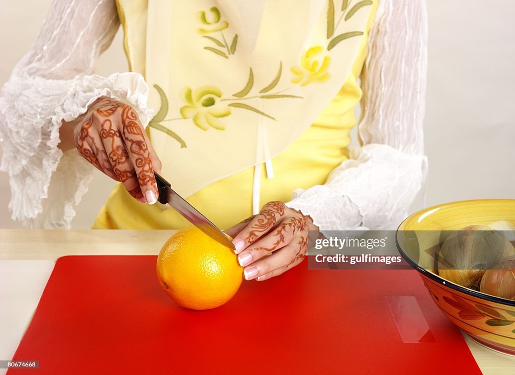 Woman cutting orange, midsection