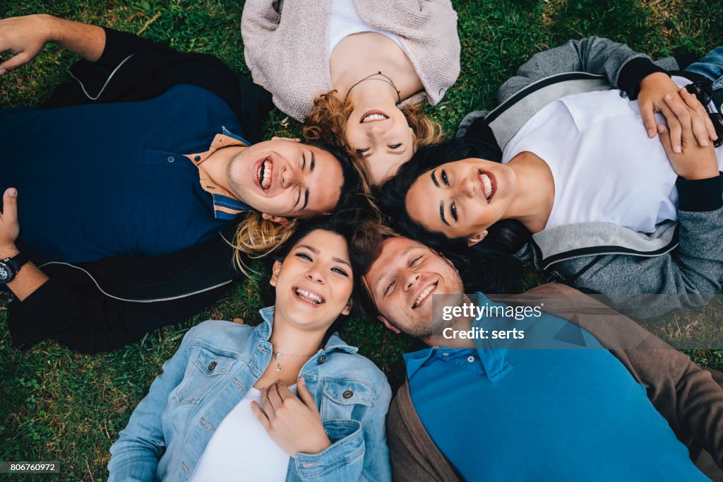 Happiness young friends lying down in the grass outside