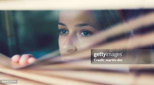infeliz mujer mirando por la ventana - nostalgia emoción fotografías e imágenes de stock