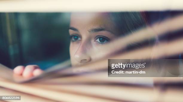 unhappy woman looking through the window - suspicion stock pictures, royalty-free photos & images